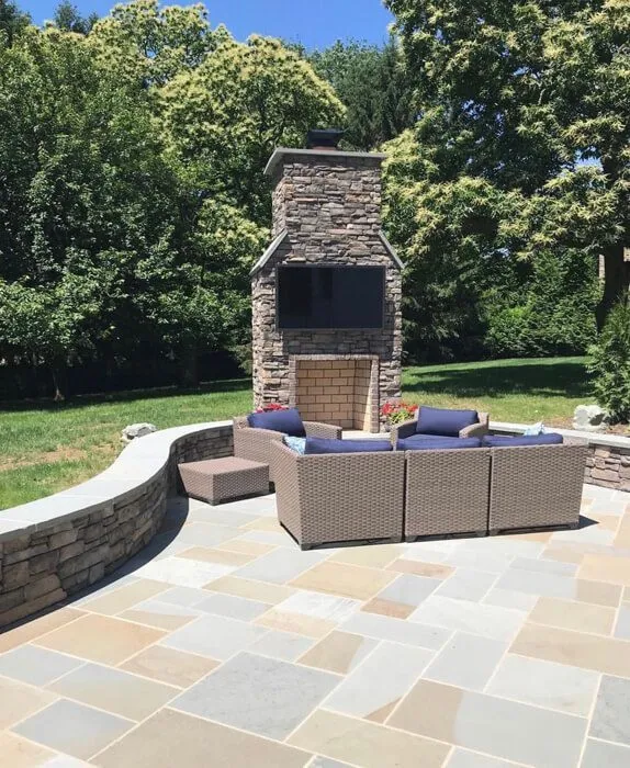 Flagstone patio with a curved seat wall and a stone chimney fireplace with TV