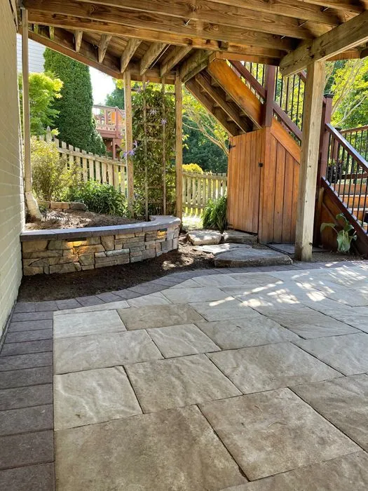 Natural flagstone patio under a covered deck with a low stone seat wall