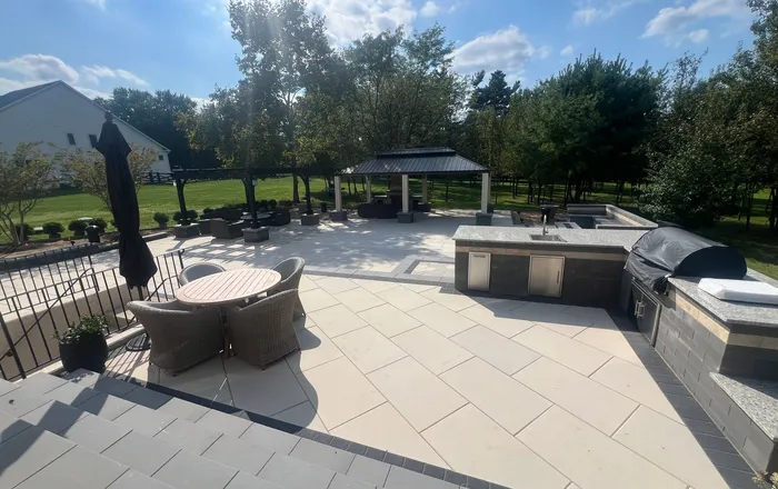 Wide paver patio with an outdoor kitchen and pavilion after releveling work in an Ellicott City, MD backyard