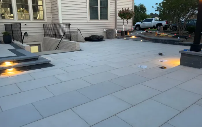 Wide bluestone paver patio with landscape lighting and steps after drainage repair at an Essex, MD home