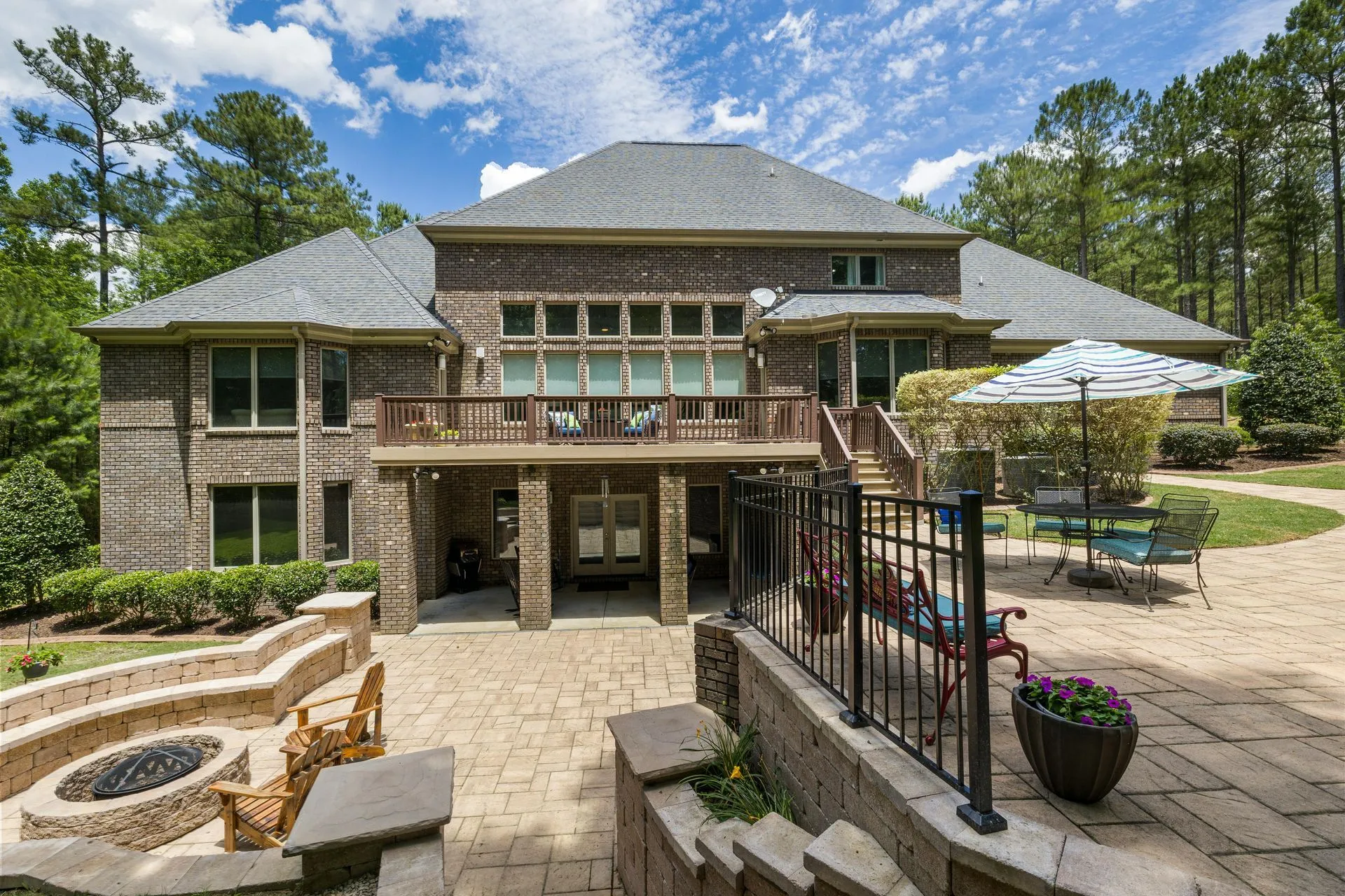 Rear exterior of a large brick home with a patio, fire pit, and seating.