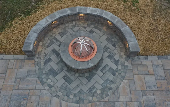 Circular paver patio with a curved stone seat wall and gas fire pit relevelled in an Overlea, MD backyard