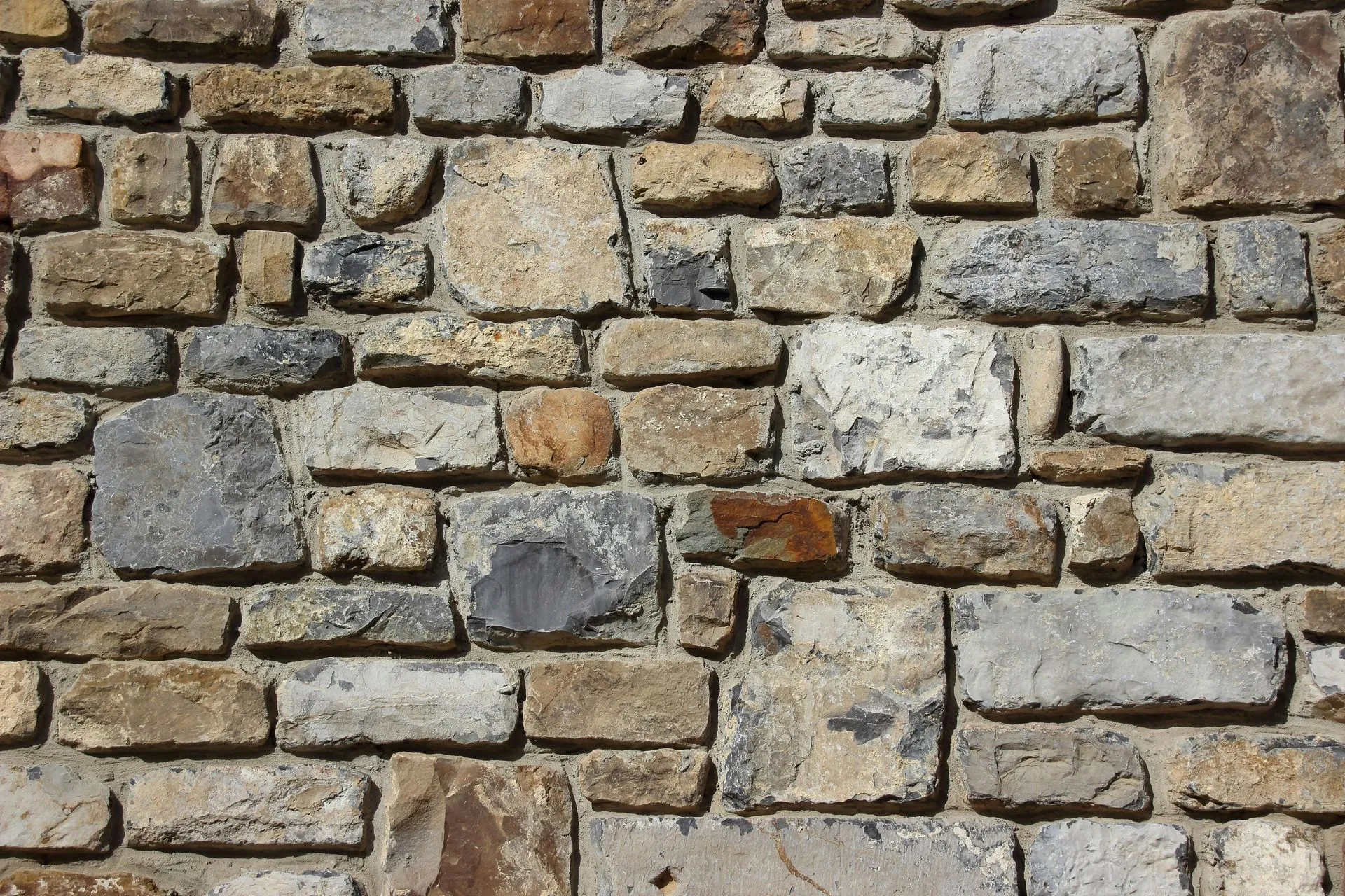 Stone brick wall, varied sizes and colors of gray, brown, and tan blocks.
