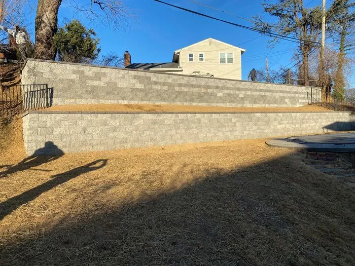 Two-tier gray block retaining wall terracing a sloped backyard